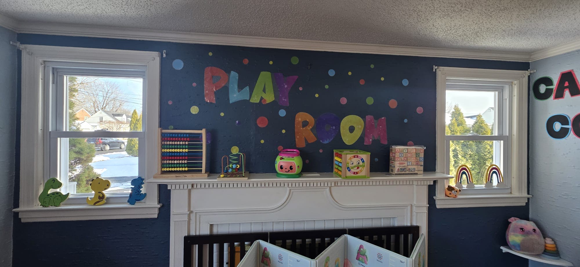 Playroom wall with "PLAY ROOM" in colorful letters, abacus, and toys on a shelf