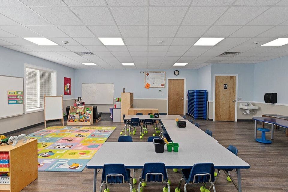 Empty classroom with tables, chairs, and a colorful rug