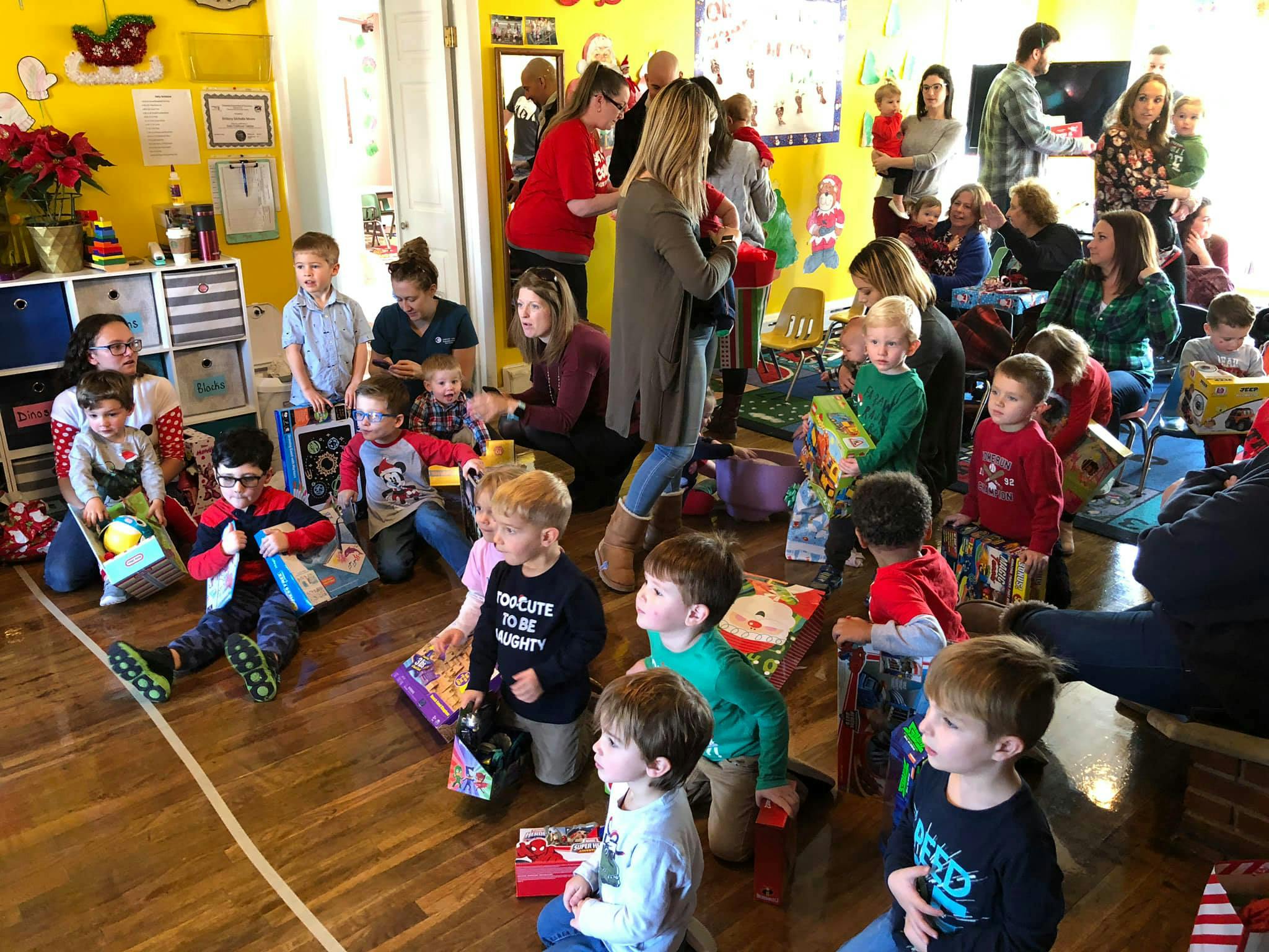 Adults and children gathered in a room with gifts