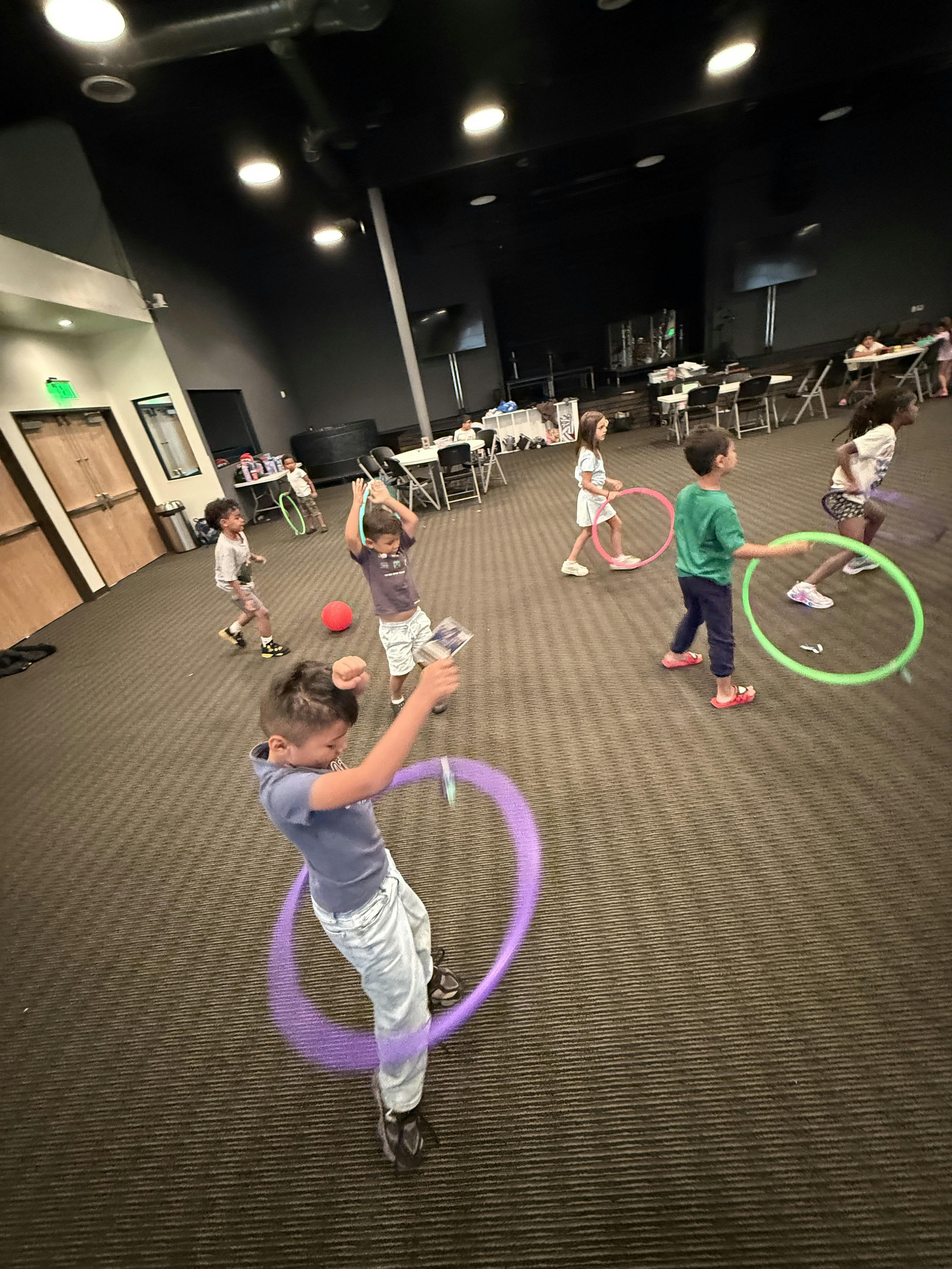Group of children playing with hula hoops in a large room