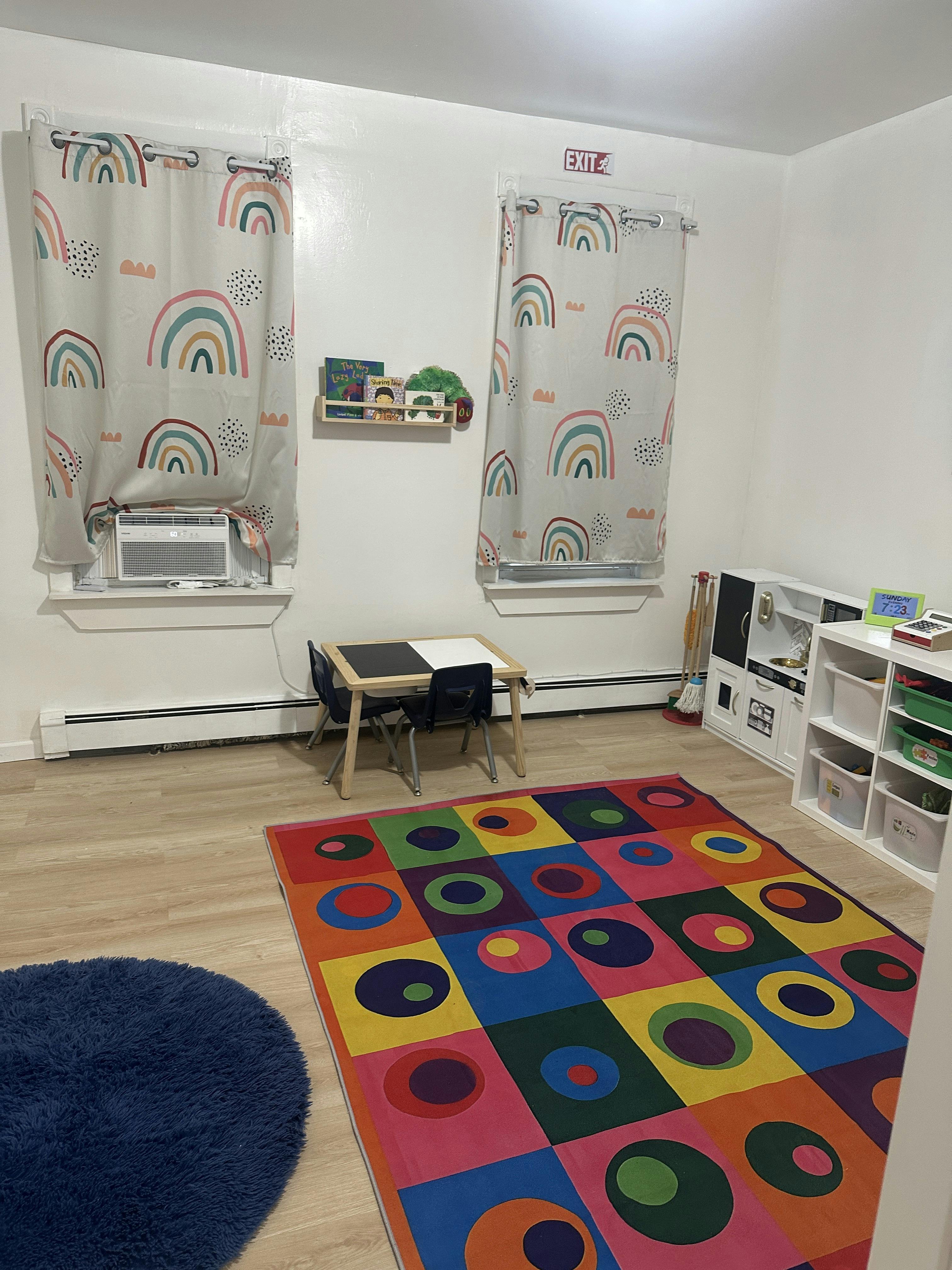 Playroom with colorful rug, small table and chairs, and toy storage