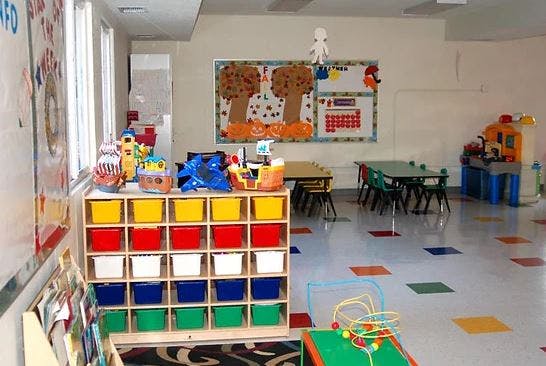 Classroom with colorful storage bins, small tables, and wall decorations