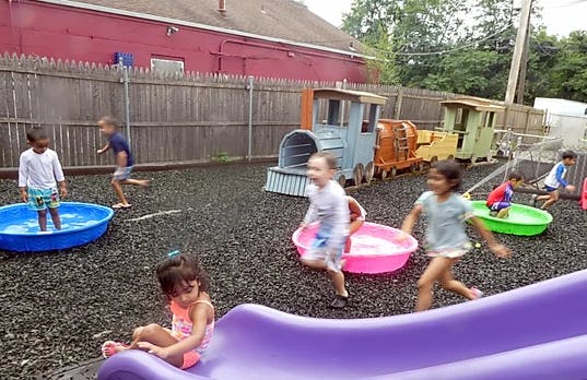 Children playing in a playground with water tubs and a slide