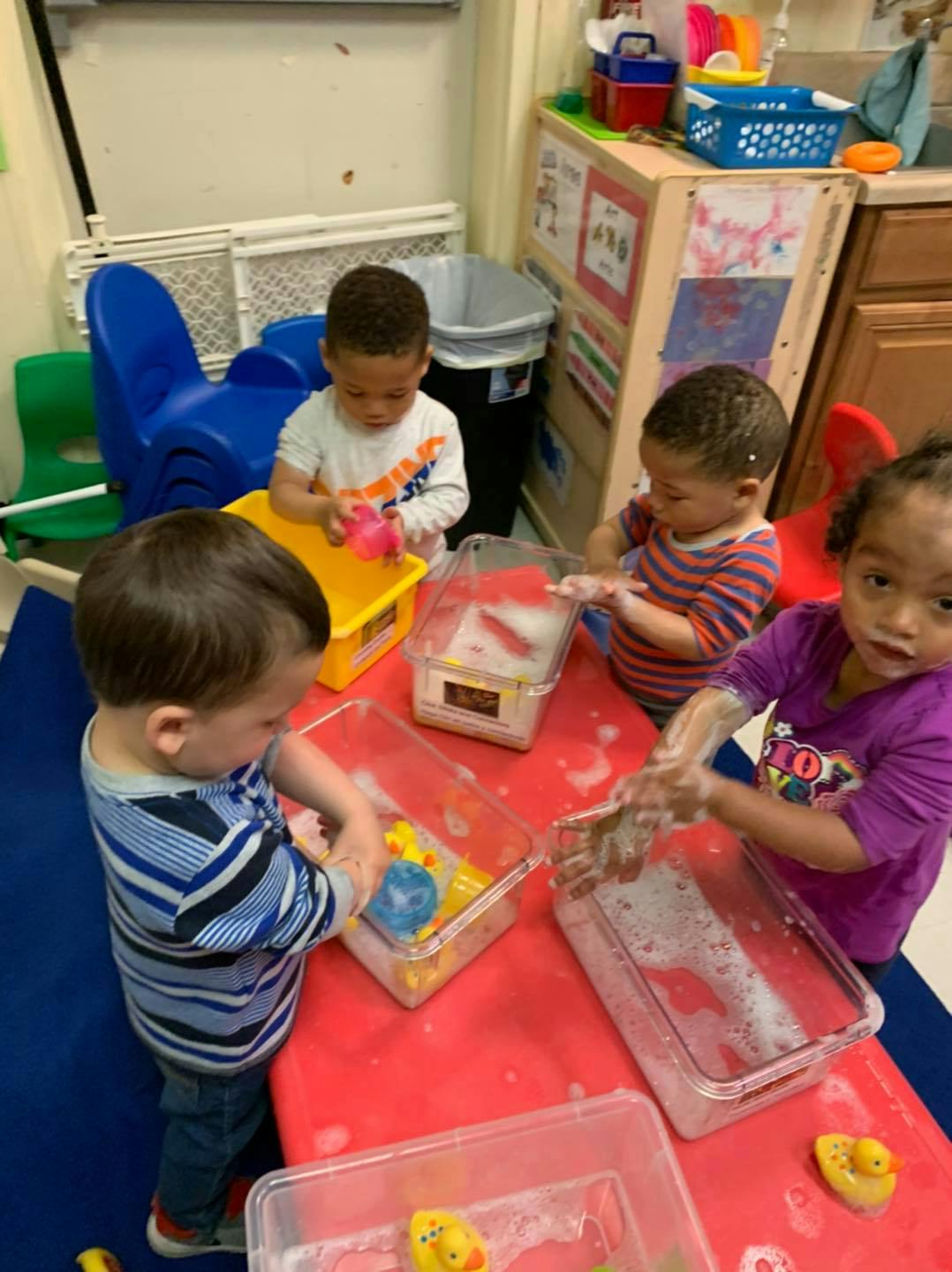 Children playing with water and bubbles in clear bins