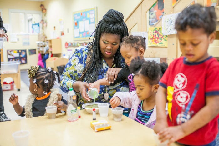 Person and children at a table pouring liquid into a bowl
