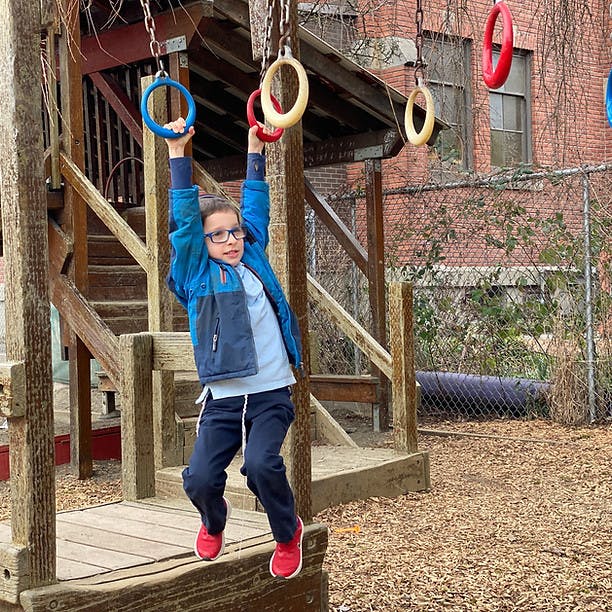 Child hanging from monkey rings on a playground