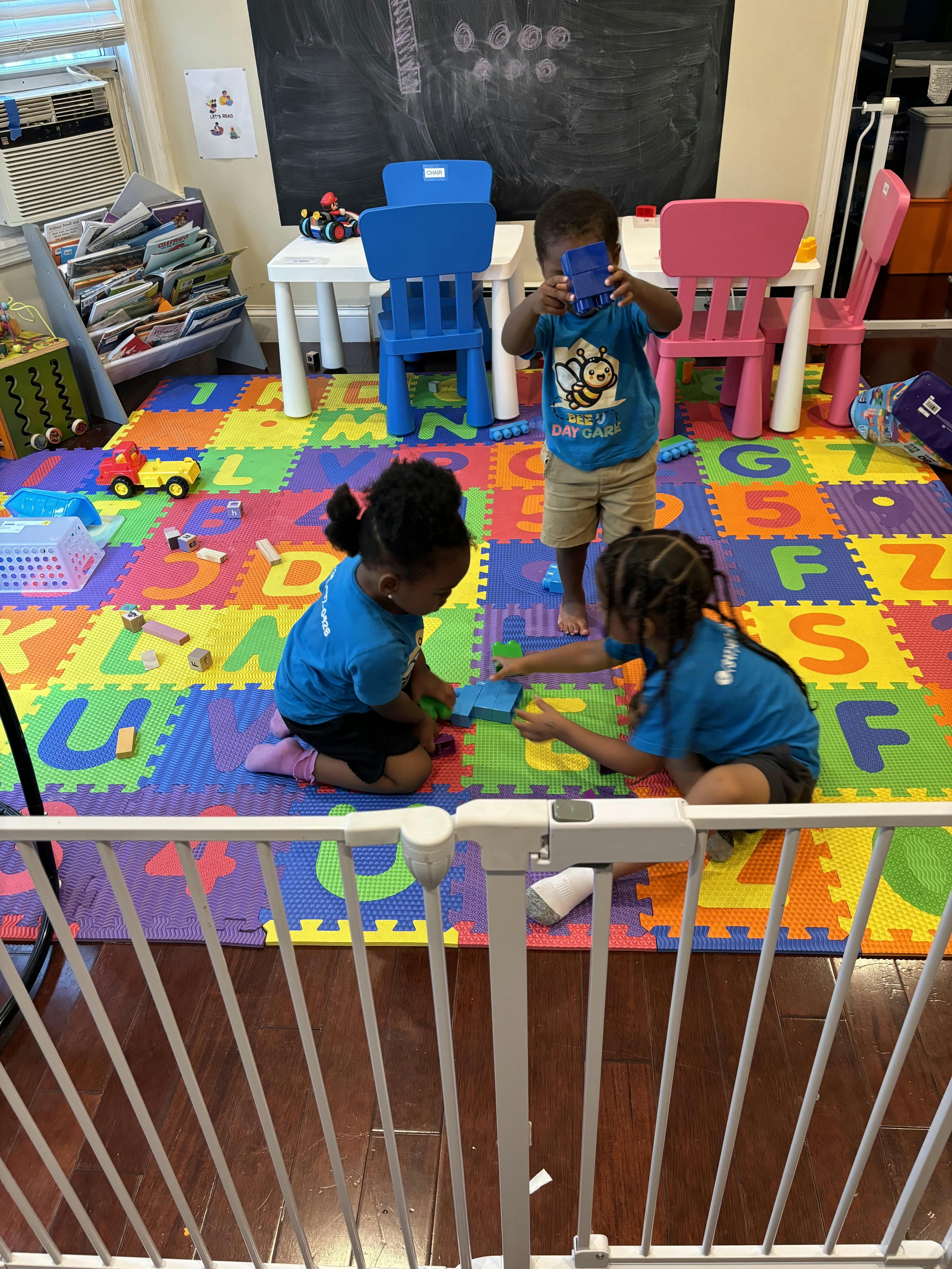 Three children playing with blocks on a colorful alphabet mat