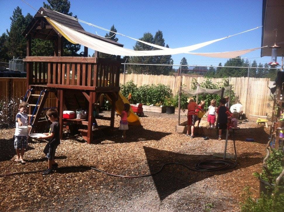 Children playing on a playground with a wooden structure and shade sails