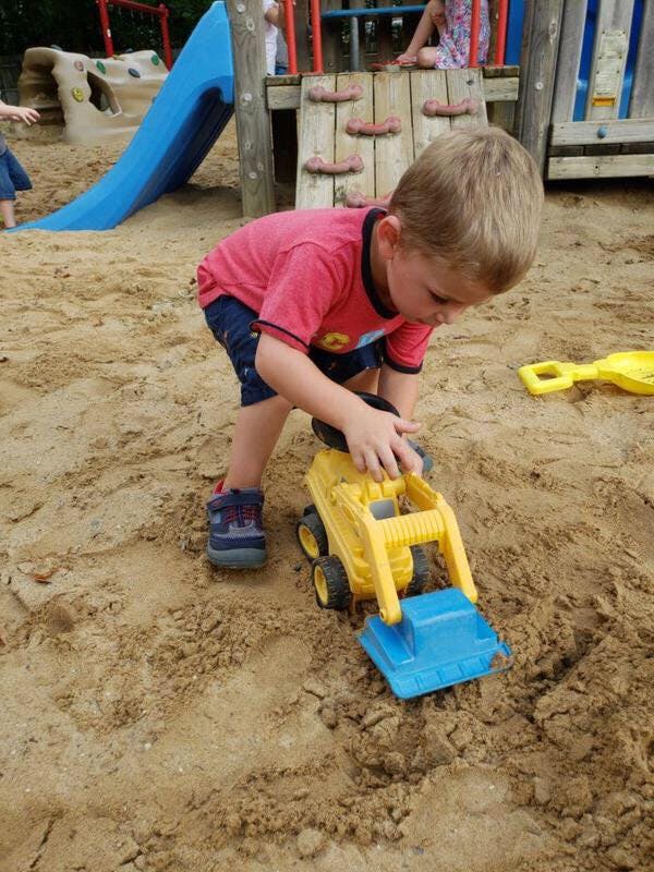 Child playing with a toy truck in a sandbox
