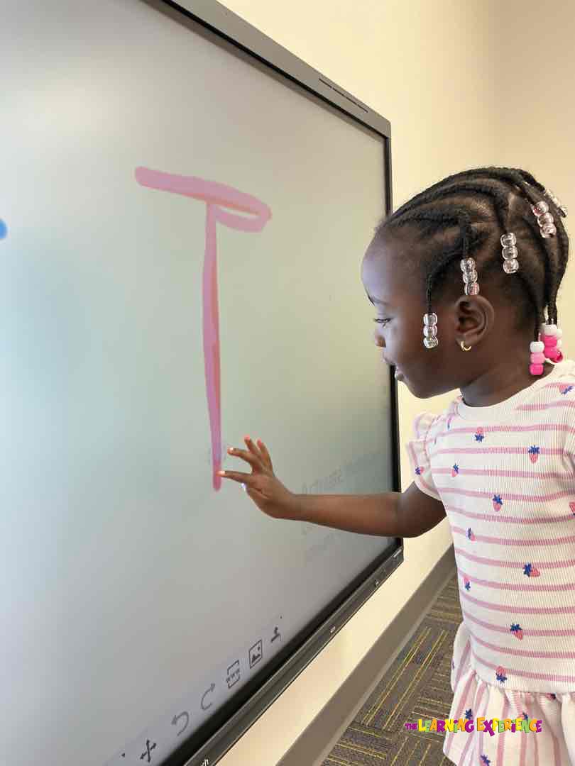 Child drawing a letter T on an interactive screen