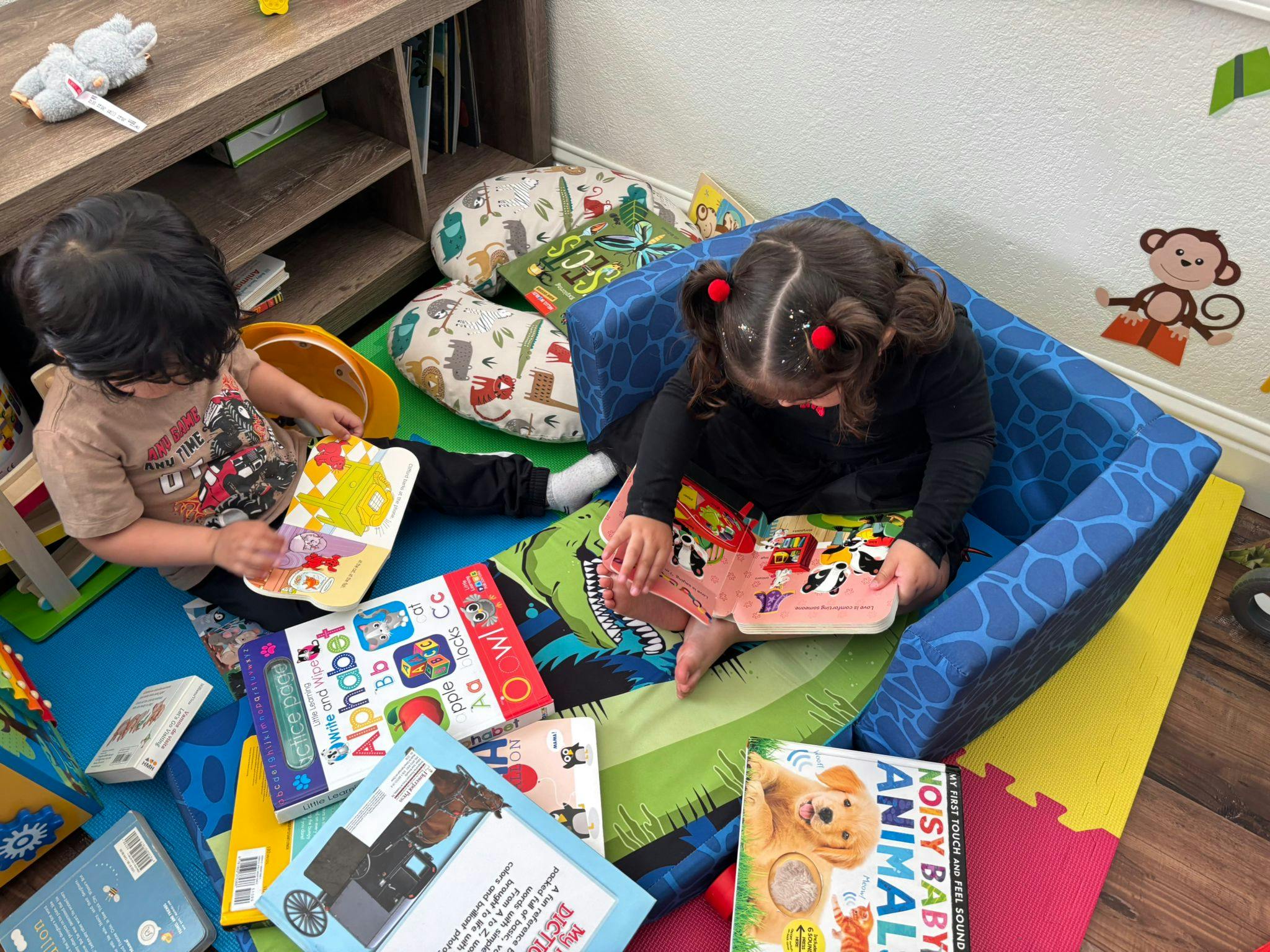 Two children sitting on the floor surrounded by books