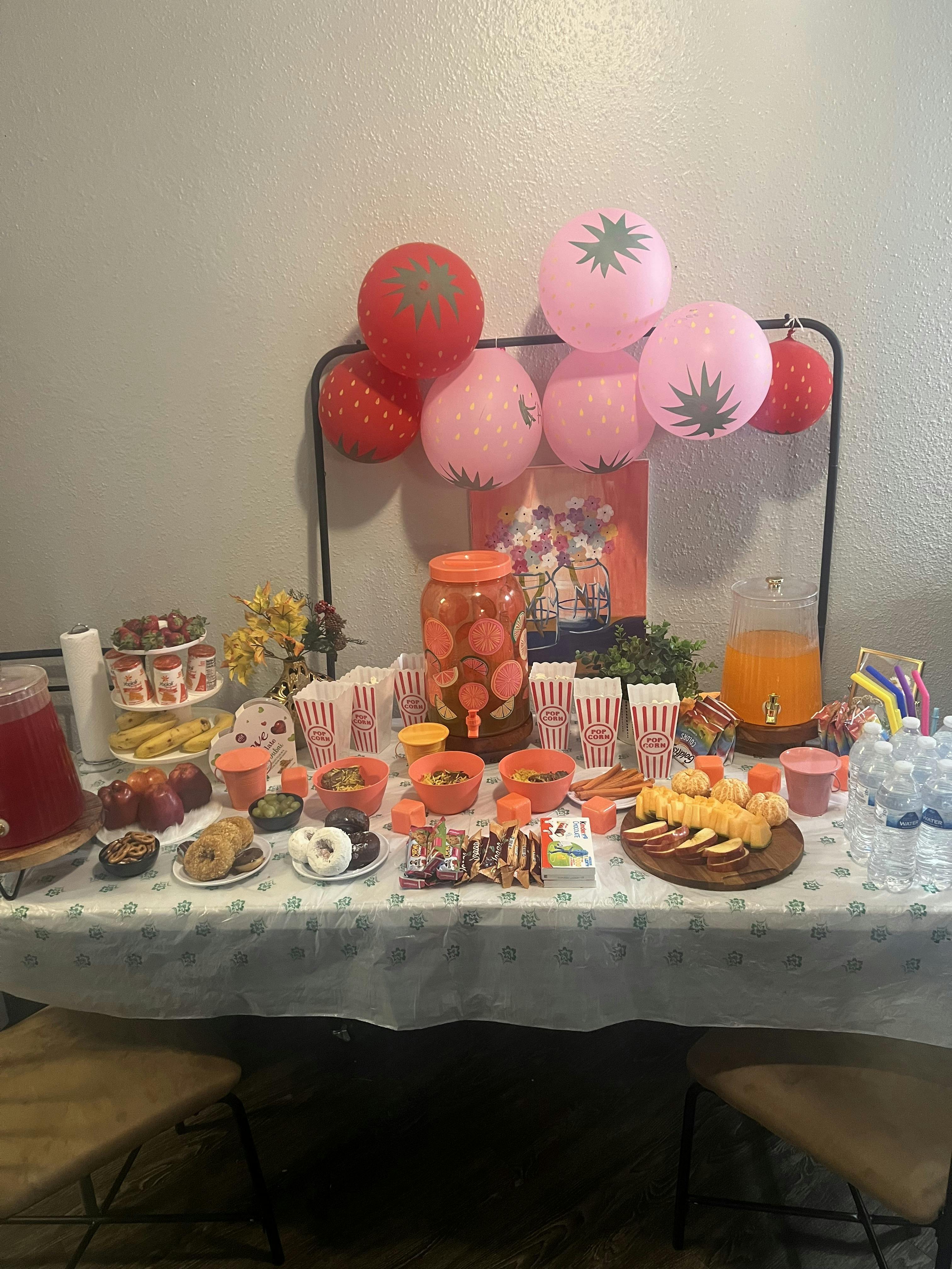 A table filled with snacks, drinks, and strawberry-themed balloons