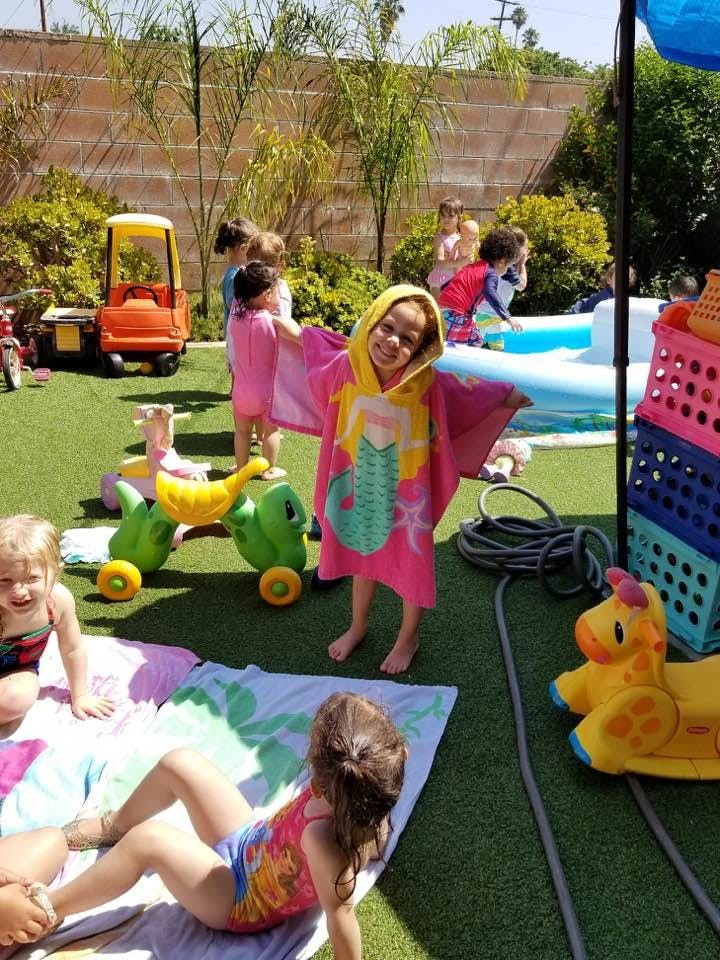 Child in a mermaid-themed hooded towel standing on grass