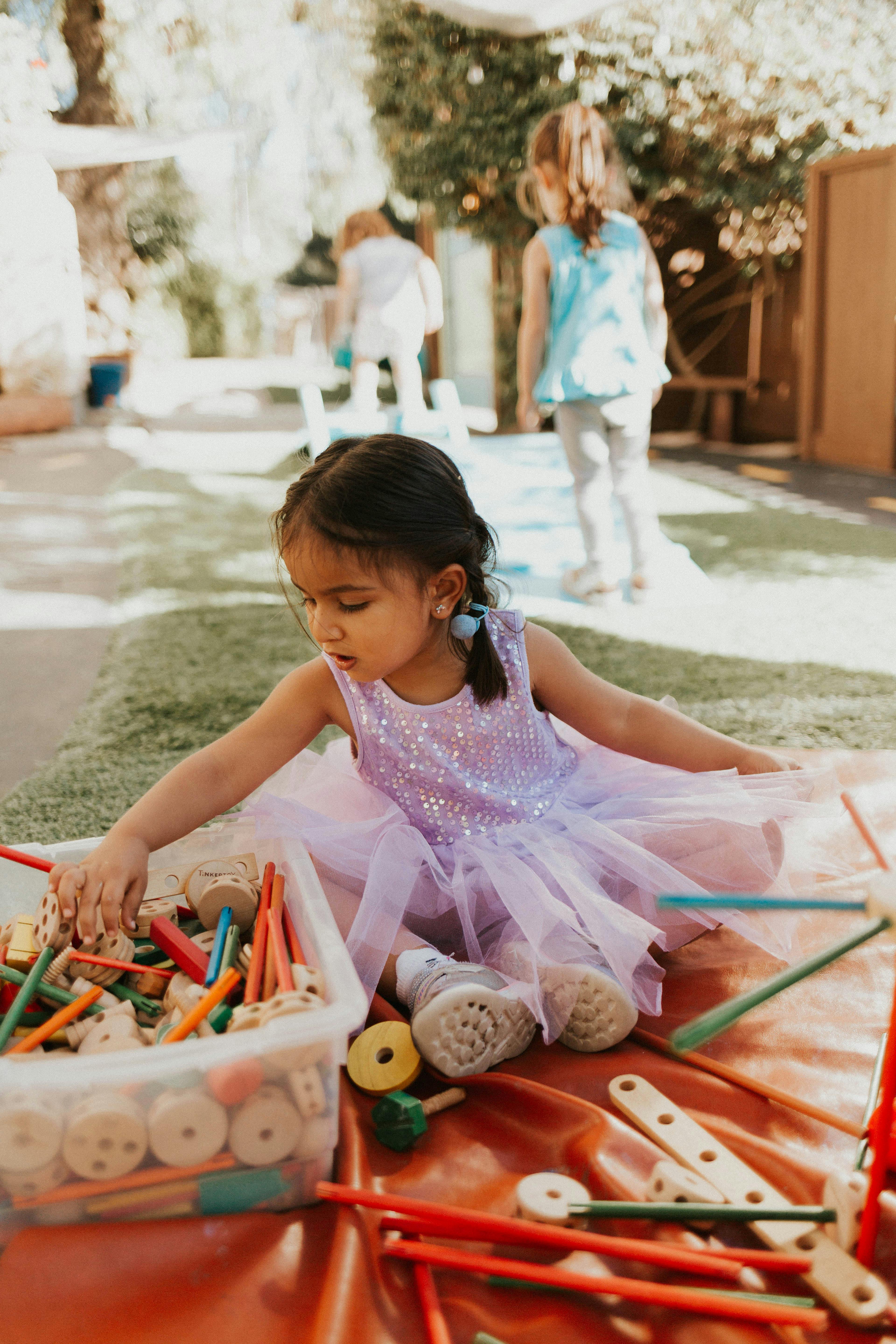 Child in a purple dress playing with building toys
