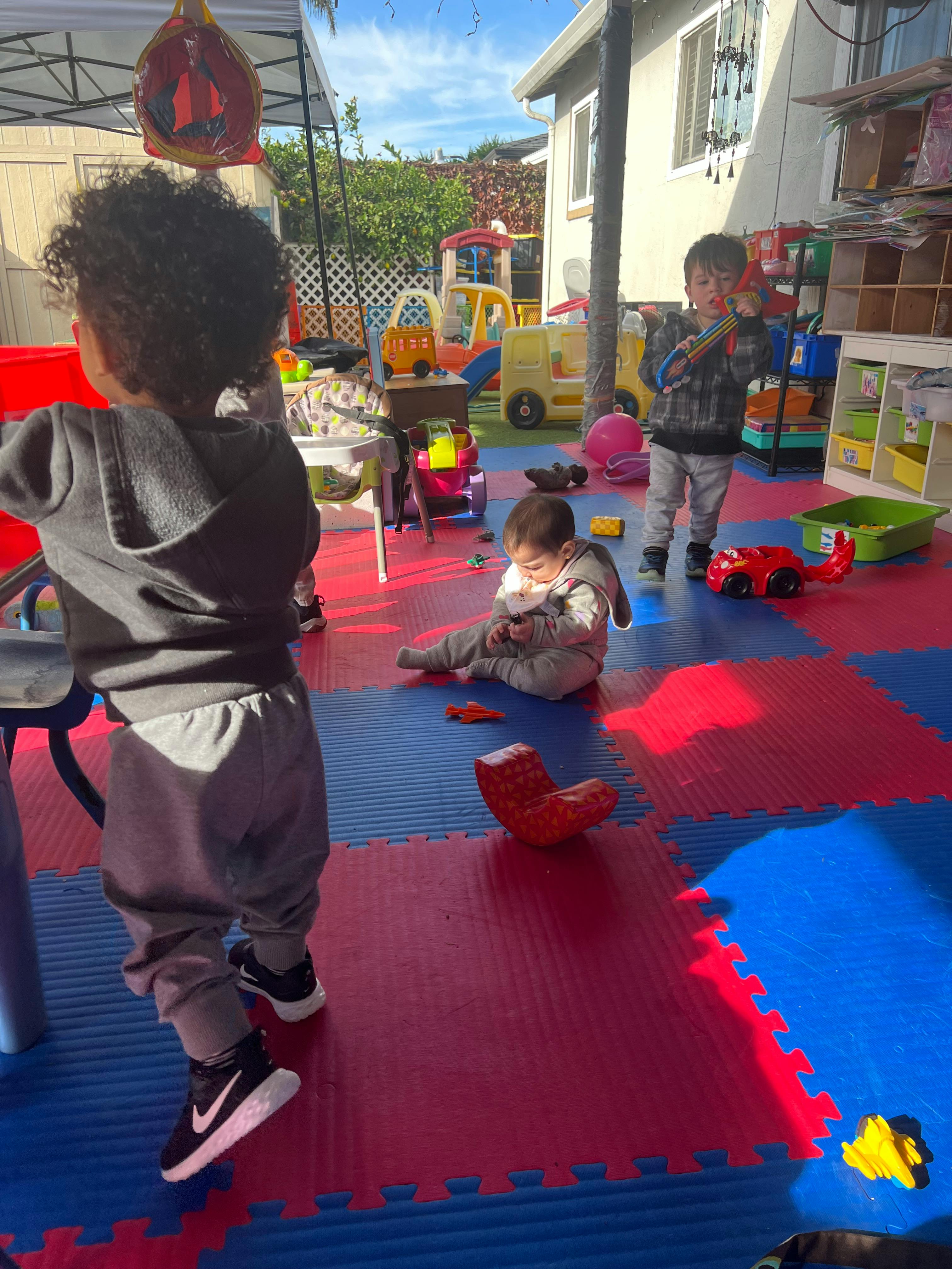 Three children playing on a red and blue mat