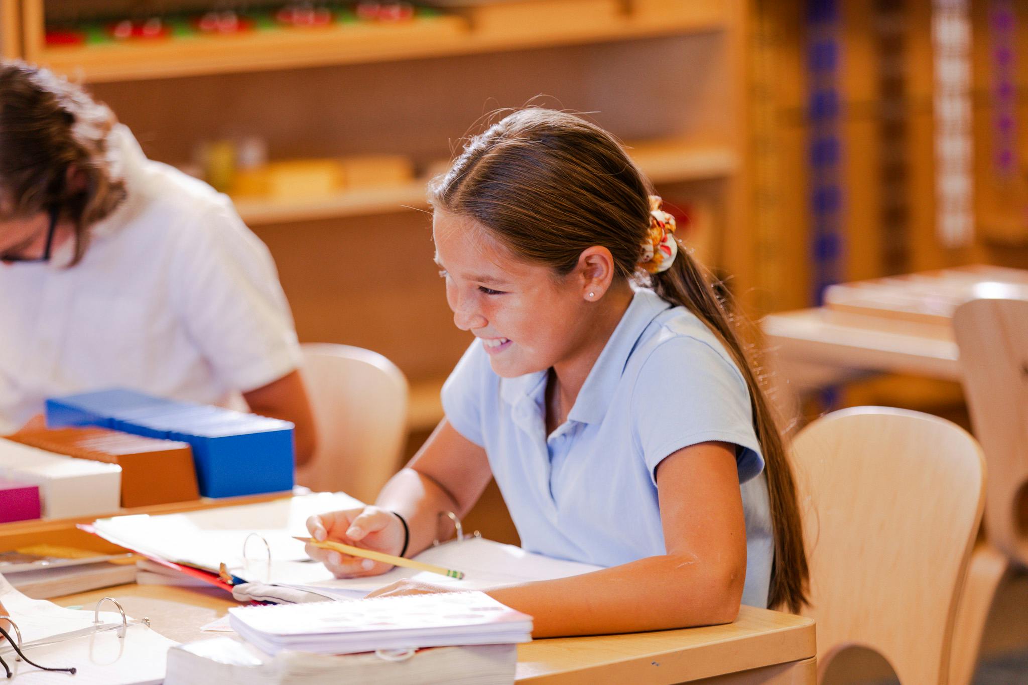 Child writing at a desk in a classroom
