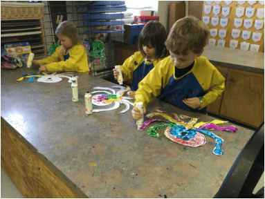 Three children painting at a table