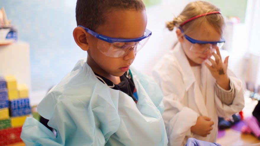 Two children wearing safety glasses and lab coats