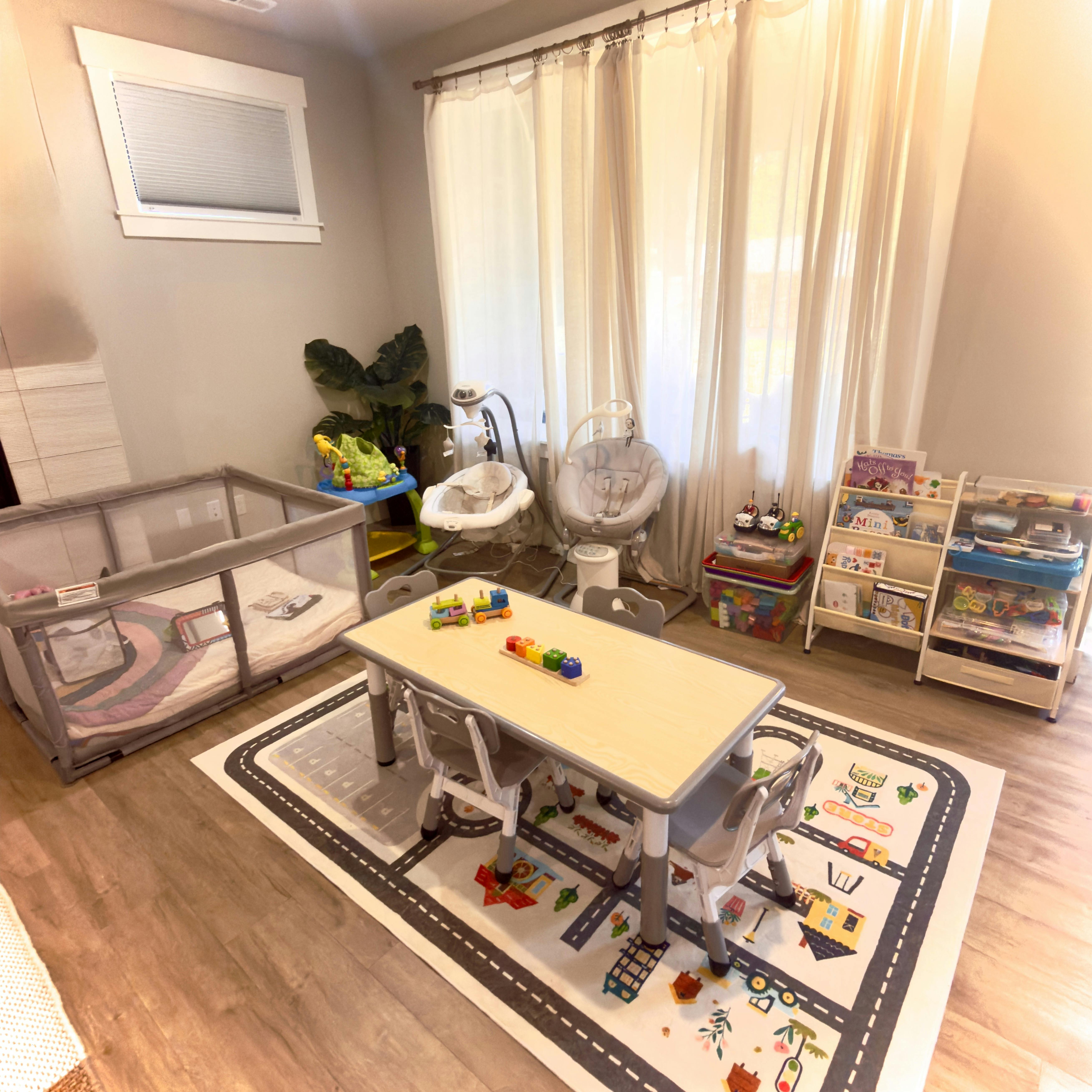 Playroom with a playpen, table with chairs, and toy storage shelves