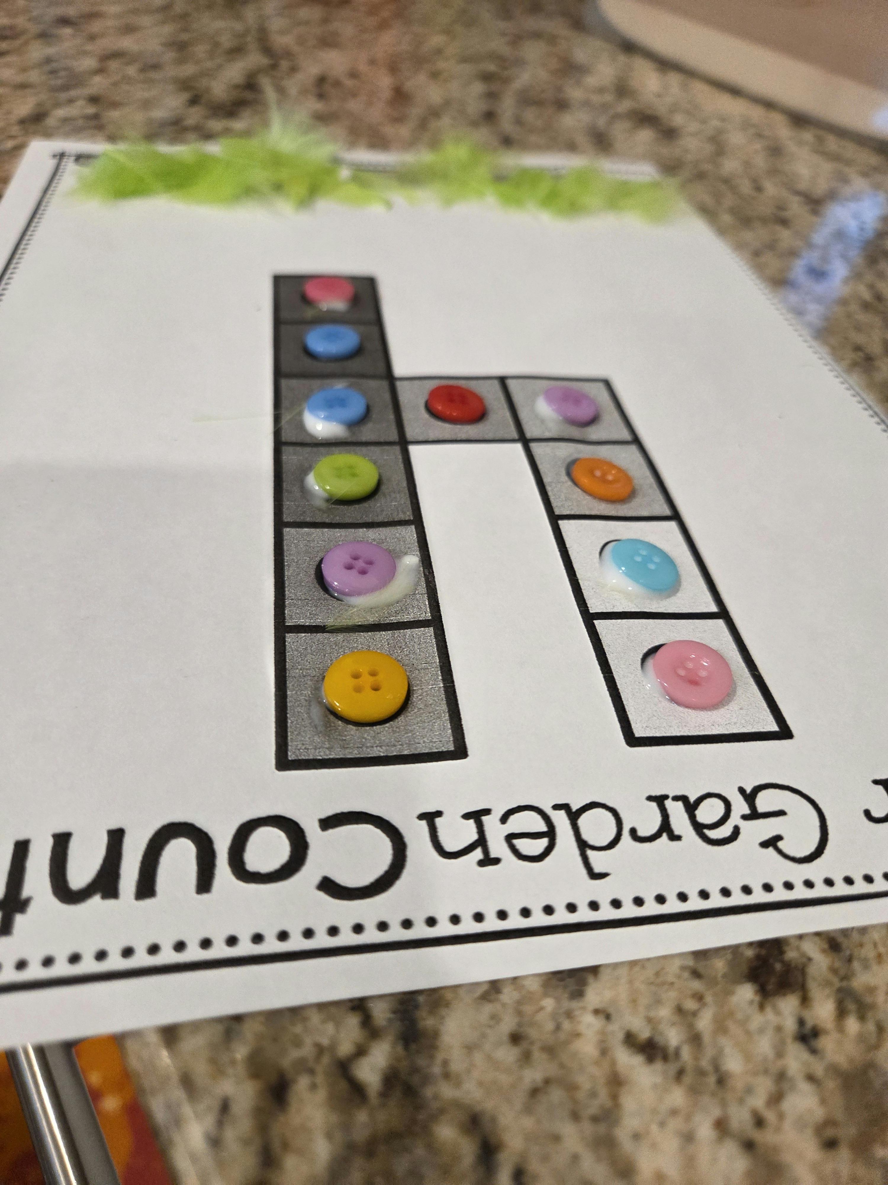 White paper with a letter 'h' outline filled with colorful buttons