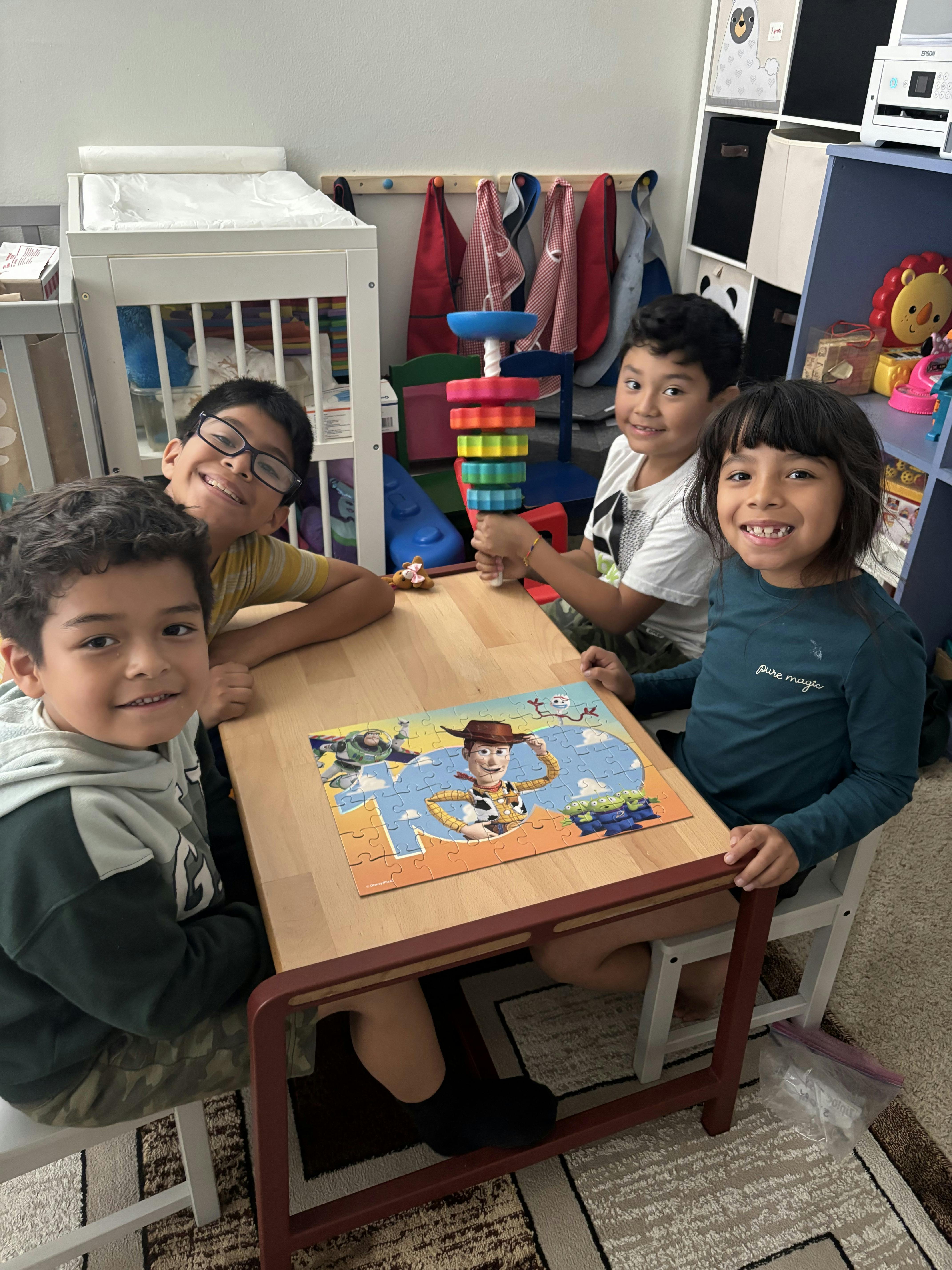 Four children sitting at a table with a Toy Story puzzle