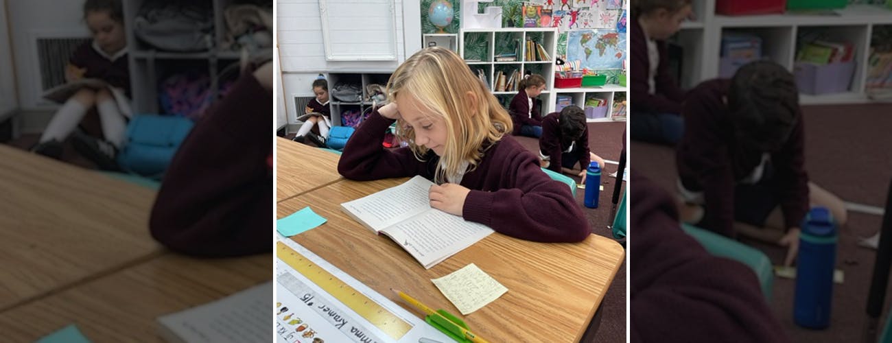 Child in a classroom reading a book at a desk