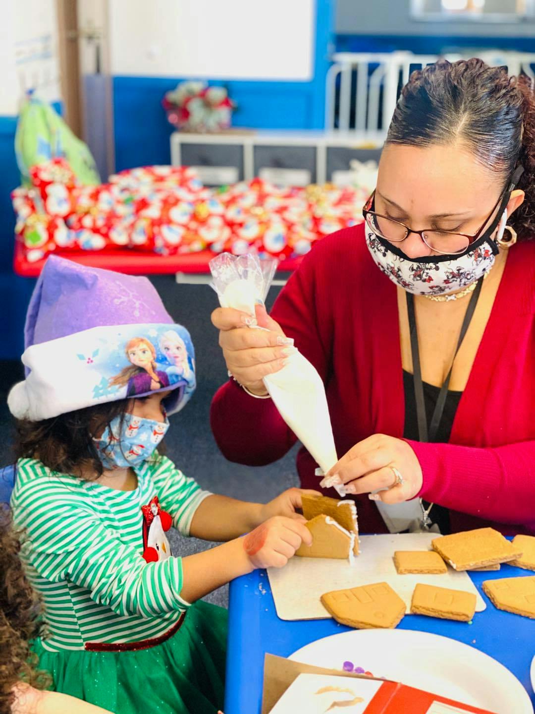 Person and child decorating gingerbread houses