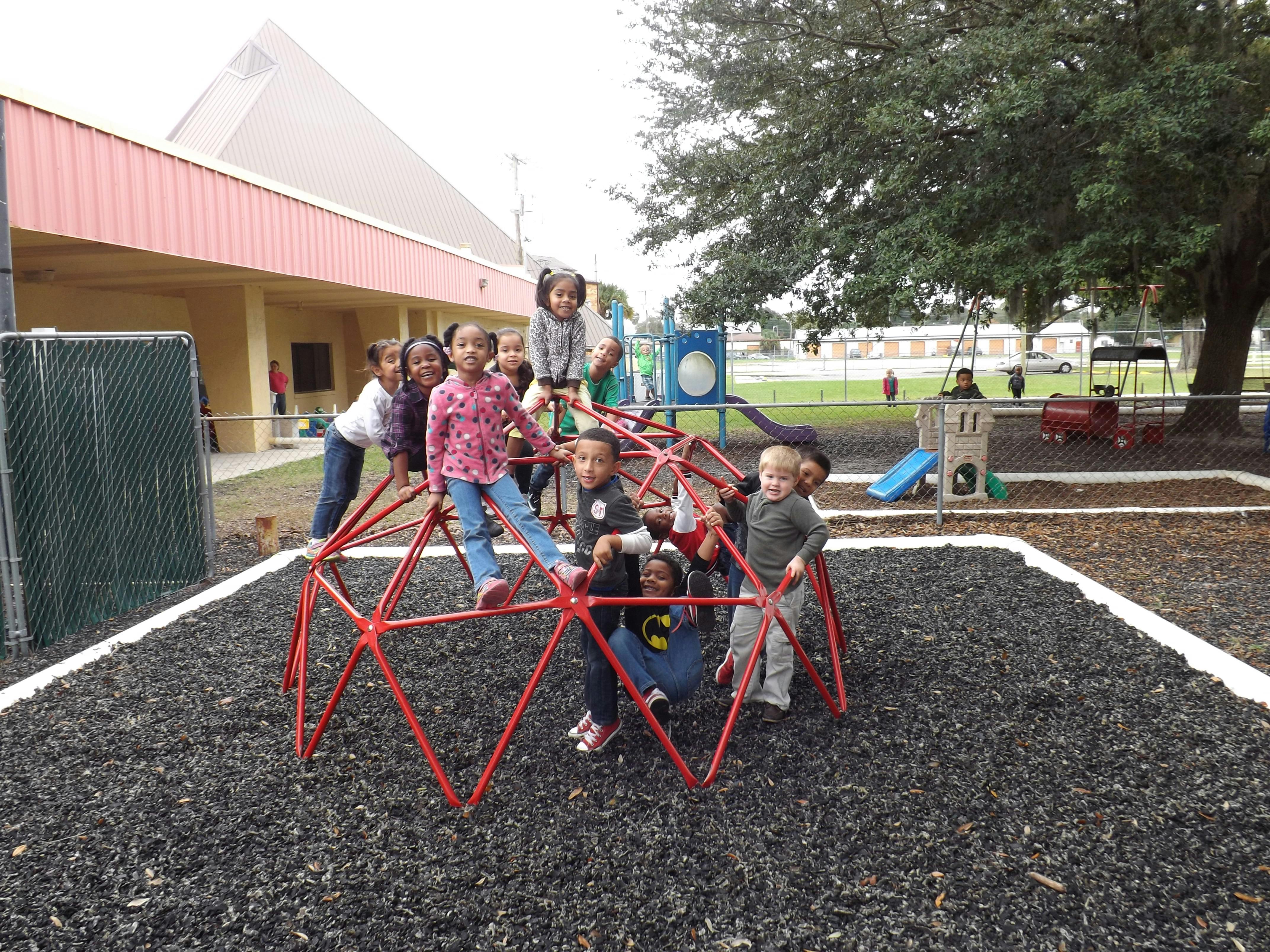 Children playing on a red climbing dome on a playground