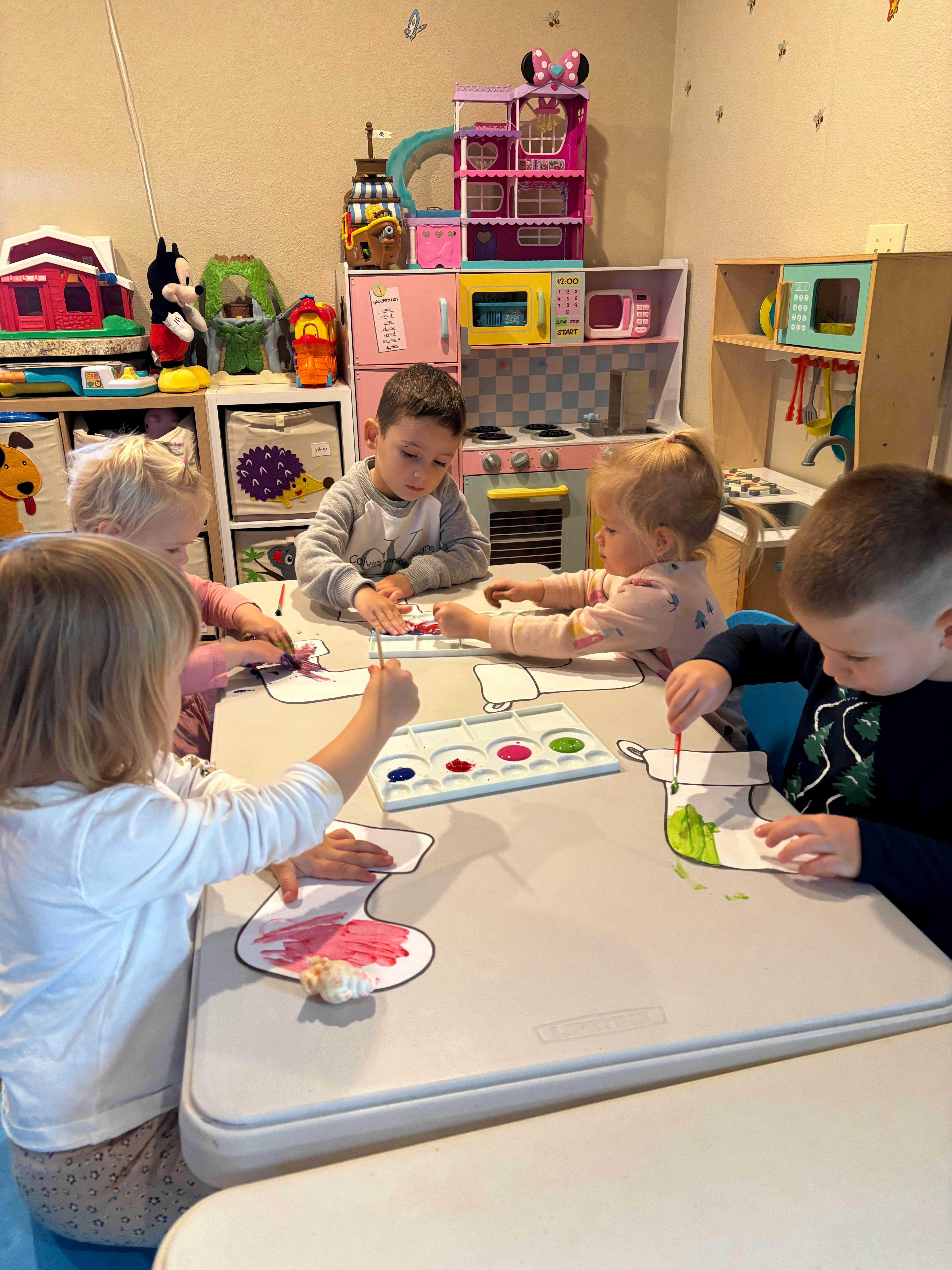 Children painting at a table in a classroom