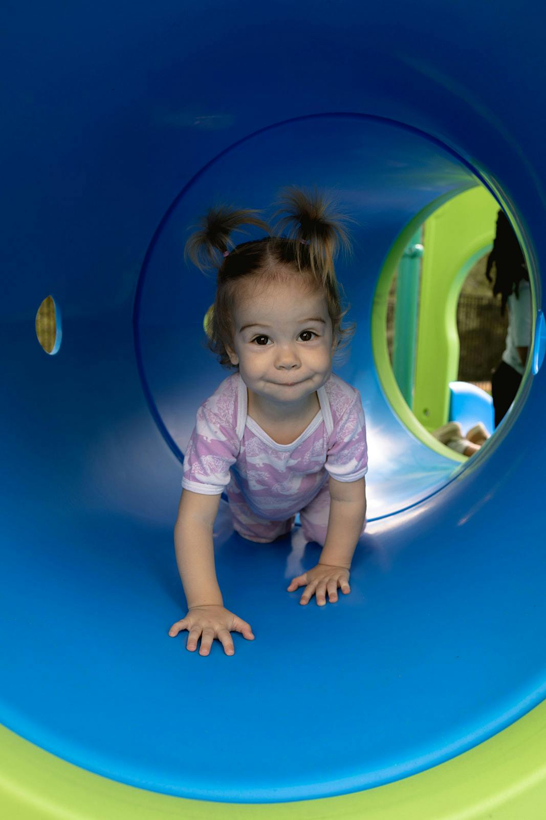 Child crawling through a blue tunnel on a playground