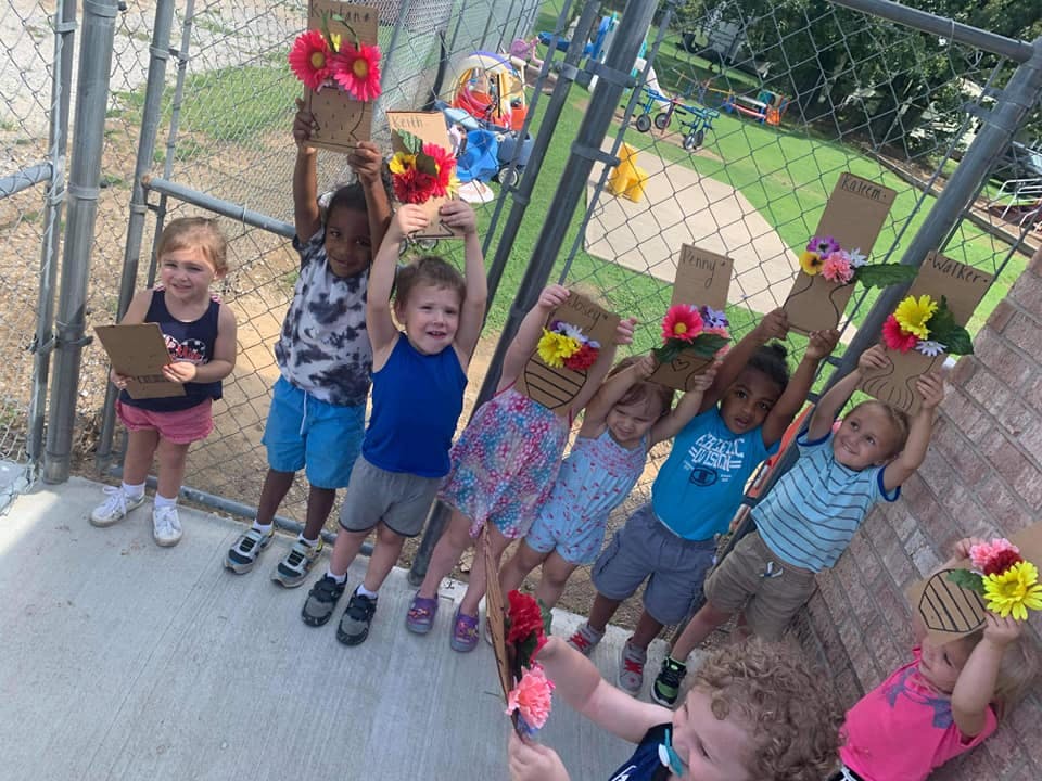 Children holding up cardboard crafts with flowers