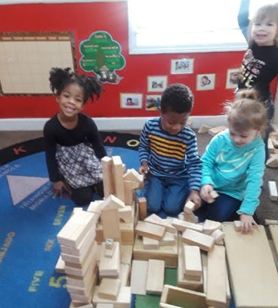 Children playing with wooden blocks in a classroom