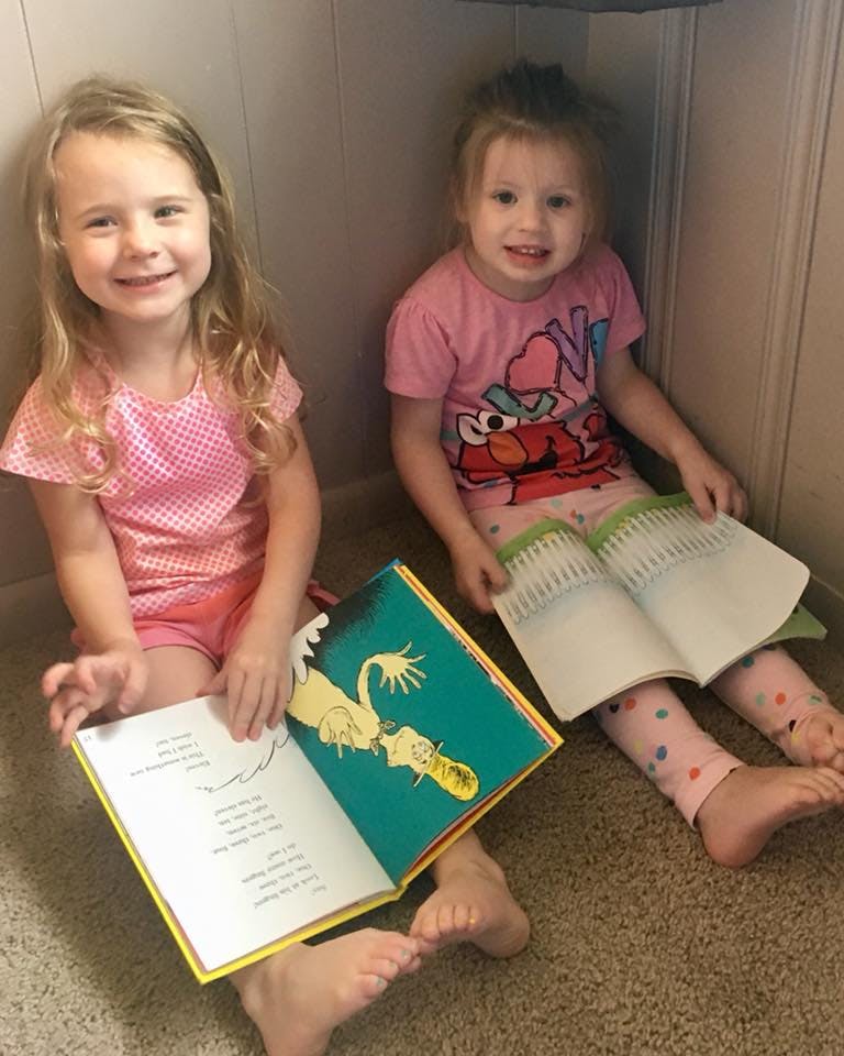 Two children sitting on the floor with open books