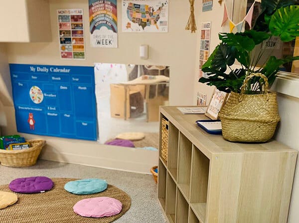 Classroom corner with a daily calendar, floor cushions, and storage shelves