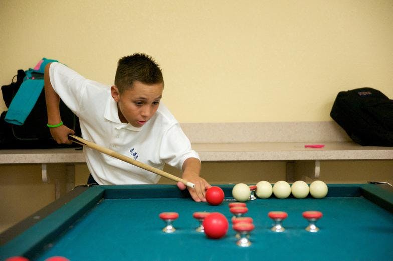 Child playing billiards with a cue stick