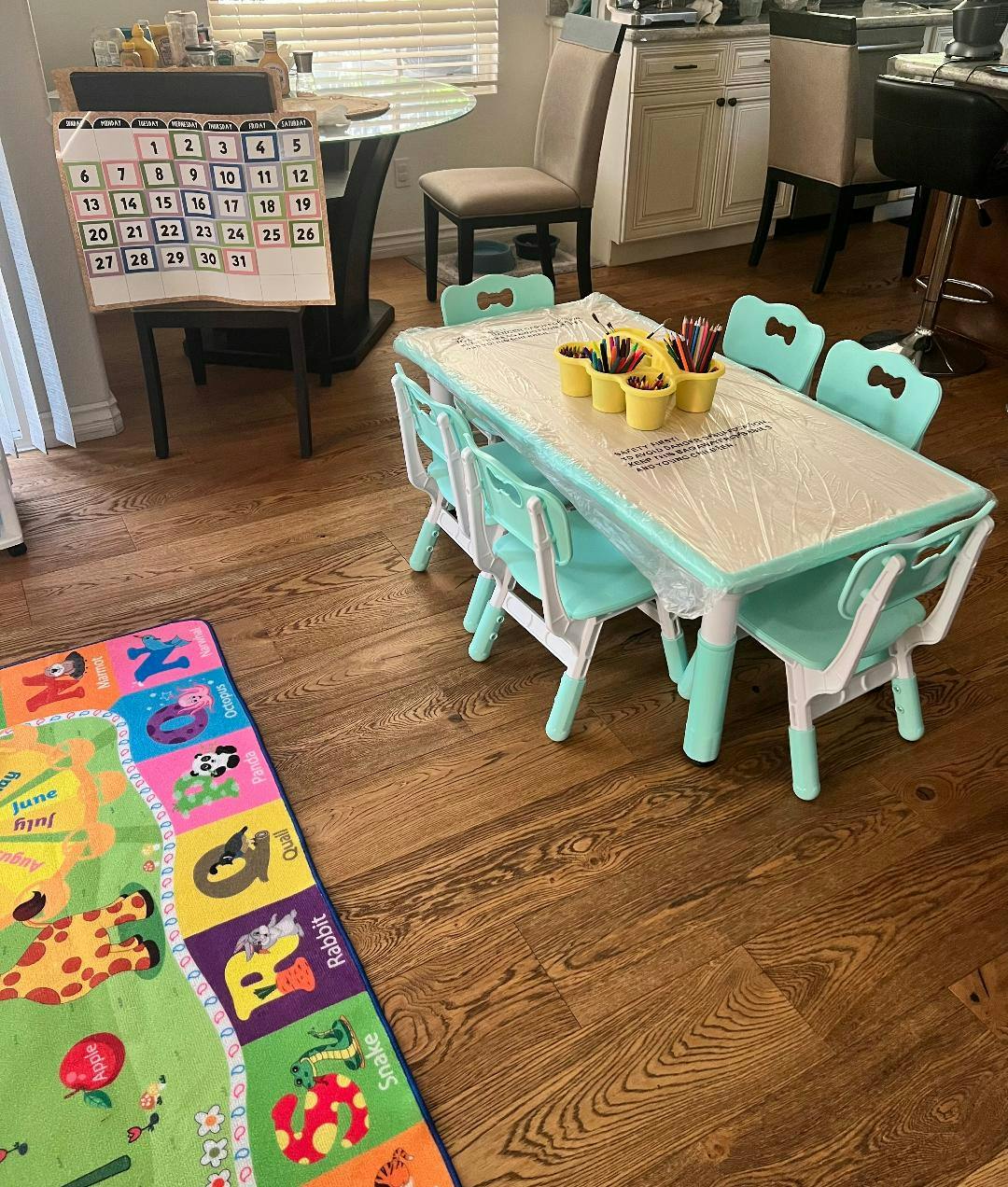 Children's table and chairs with a playmat on a wooden floor