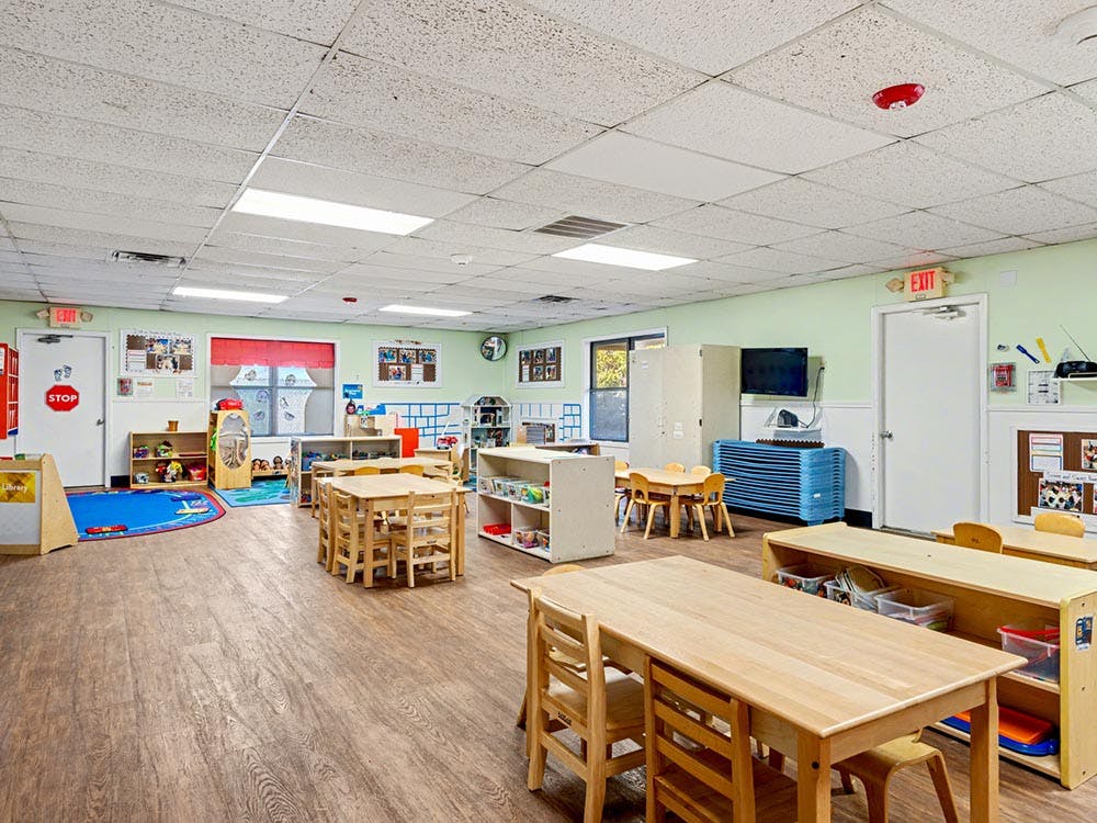 Empty preschool classroom with small tables and chairs