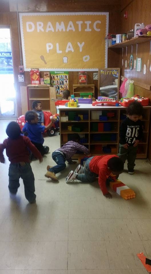 Children playing in a classroom with a "Dramatic Play" sign