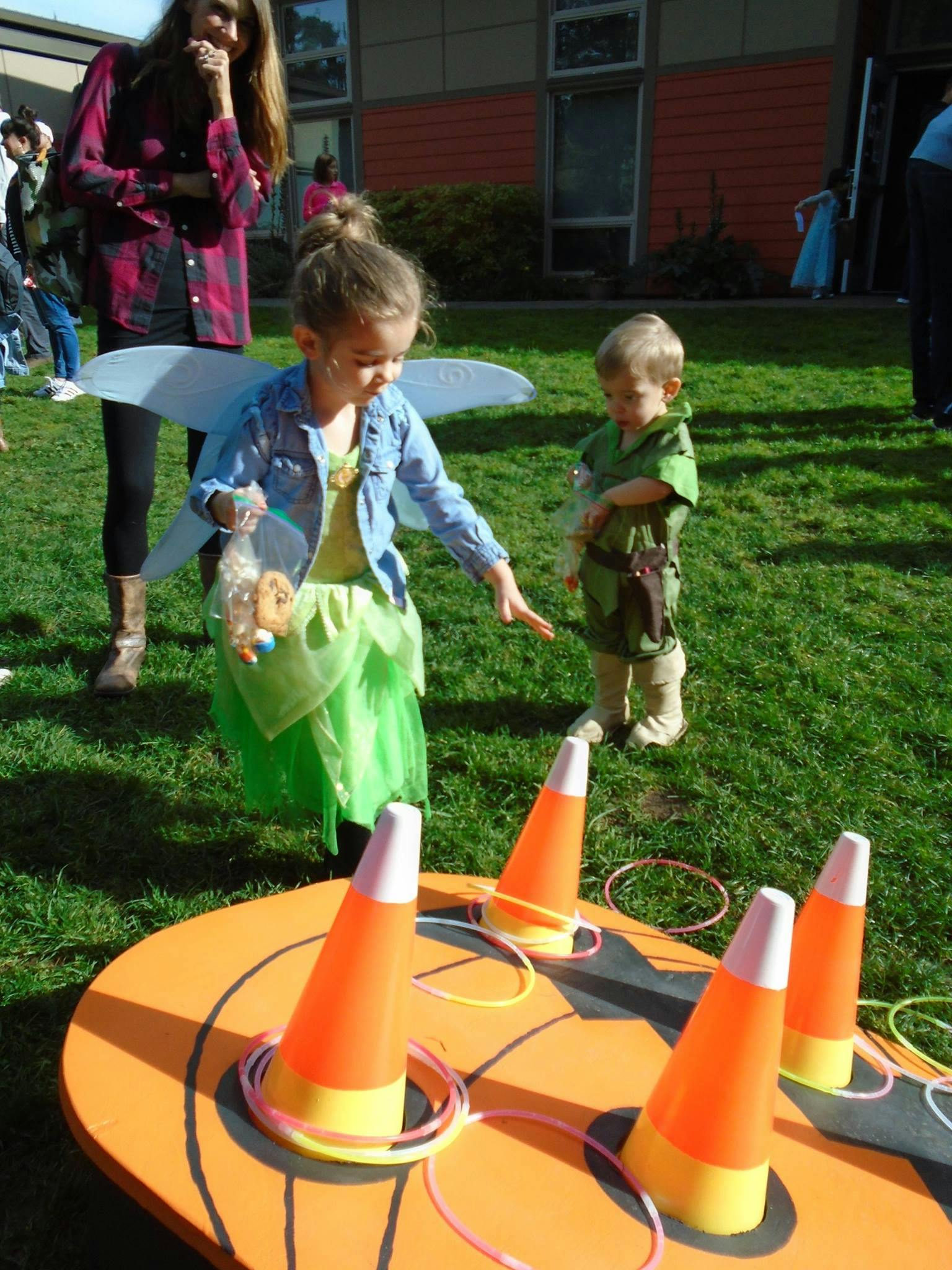Child in fairy costume playing a ring toss game with another child