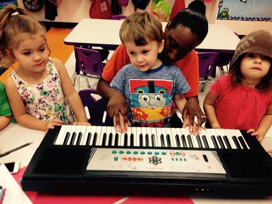 Adult and three children playing a keyboard
