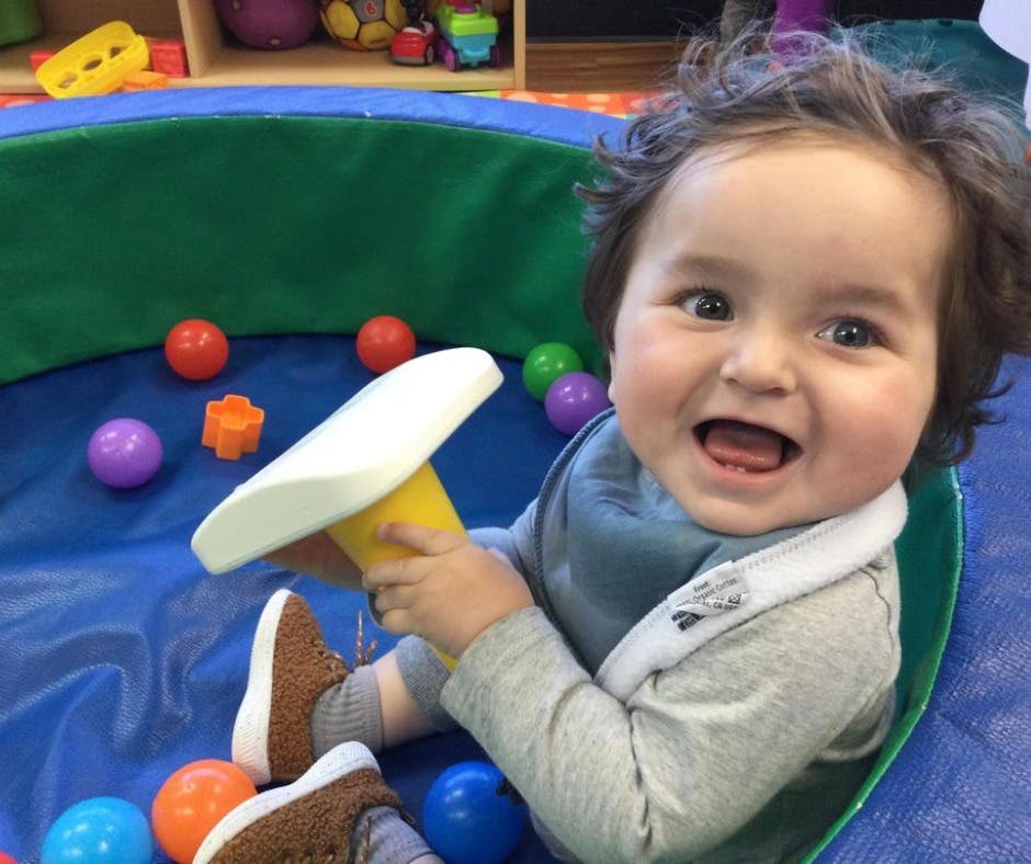 Child playing with a toy in a ball pit