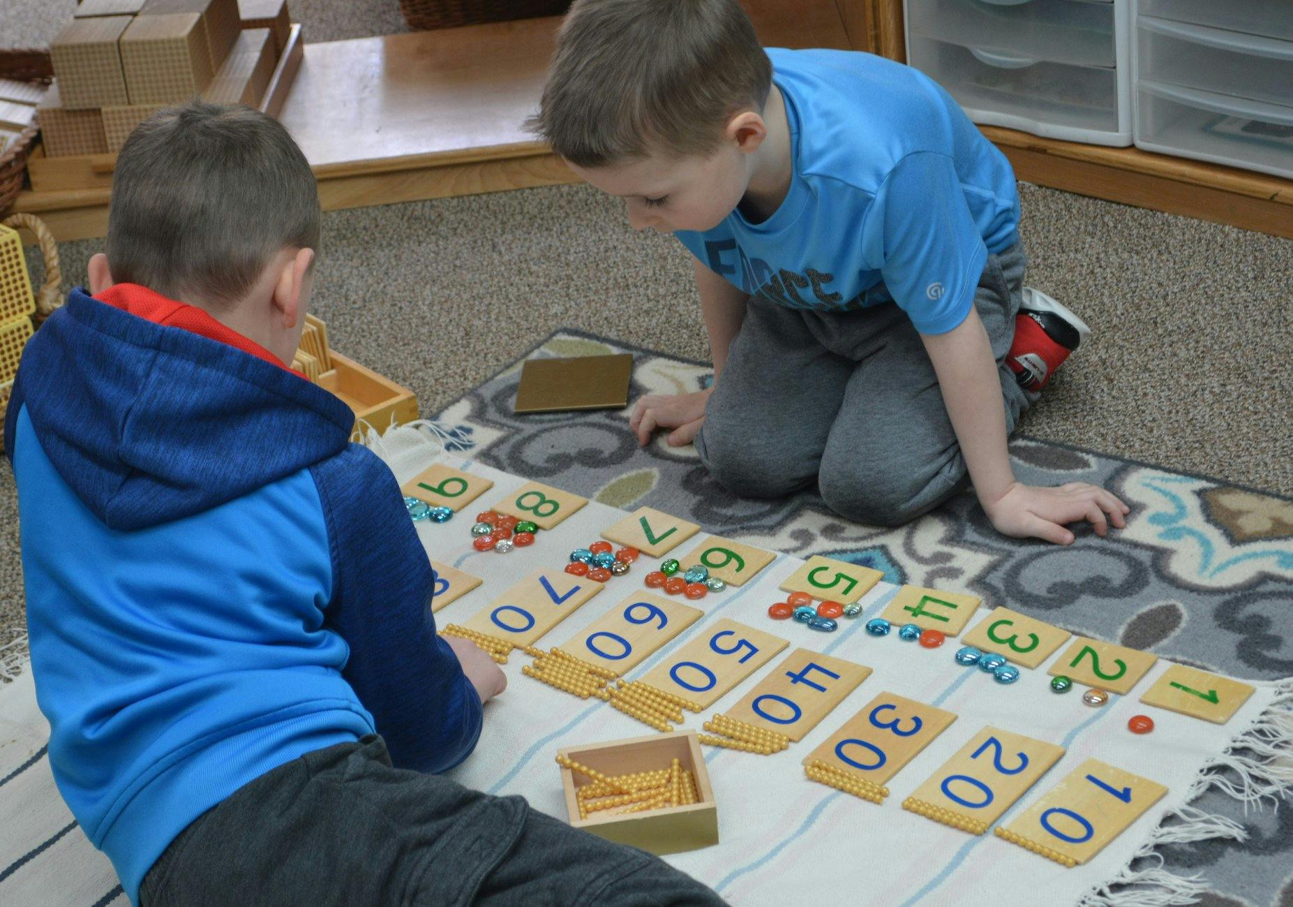 Two children playing with number cards on a rug