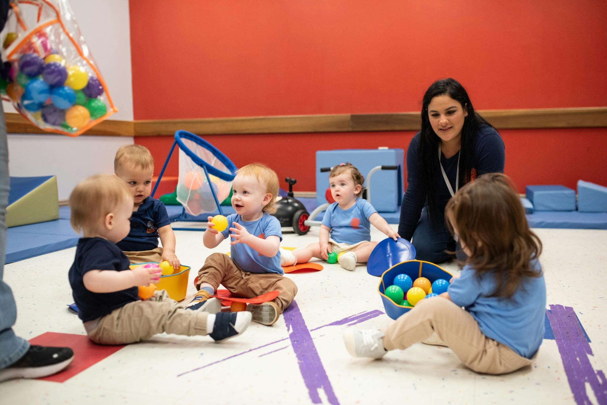 Adult supervising several children playing with colorful balls