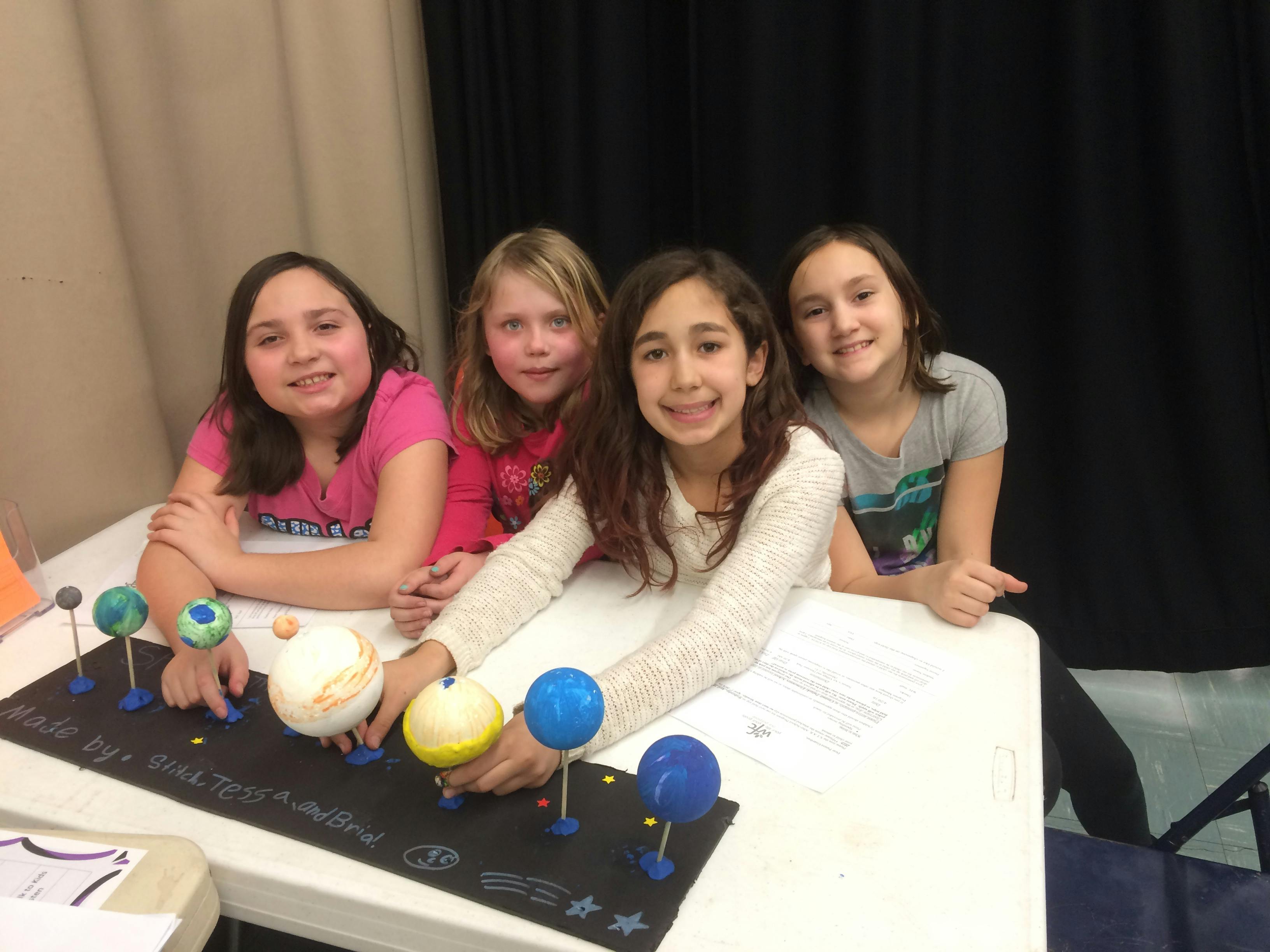 Four children with a solar system model