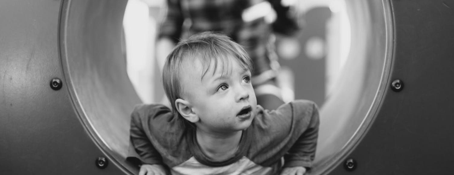 Child looking up while crawling through a tunnel