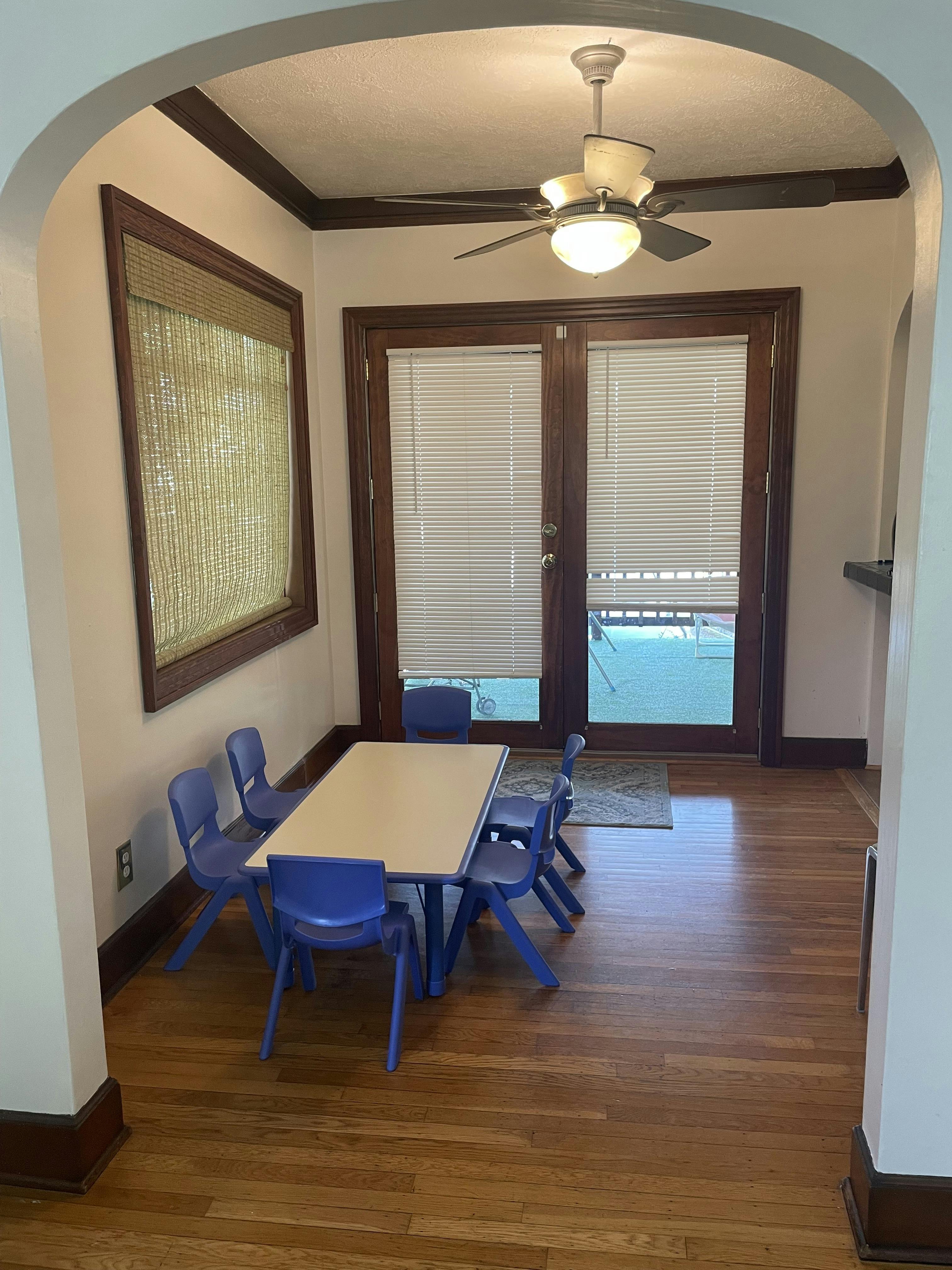 Small table with four small blue chairs in front of glass doors