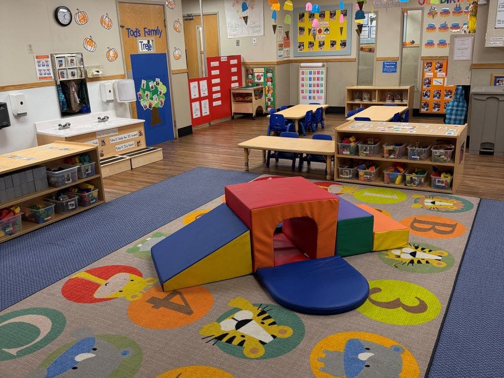 Colorful playroom with soft climbing blocks, tables, chairs, and shelves of toys
