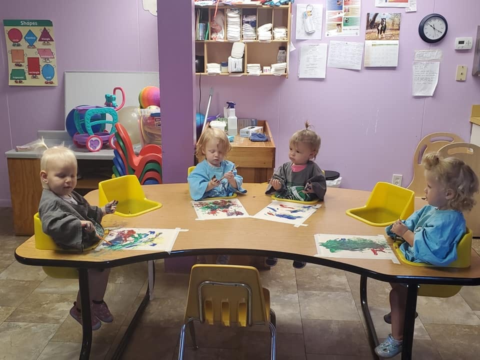 Four children sitting at a table painting