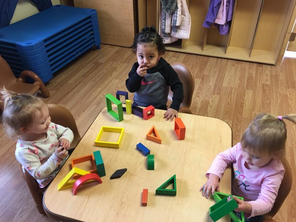 Three children playing with colorful blocks at a table