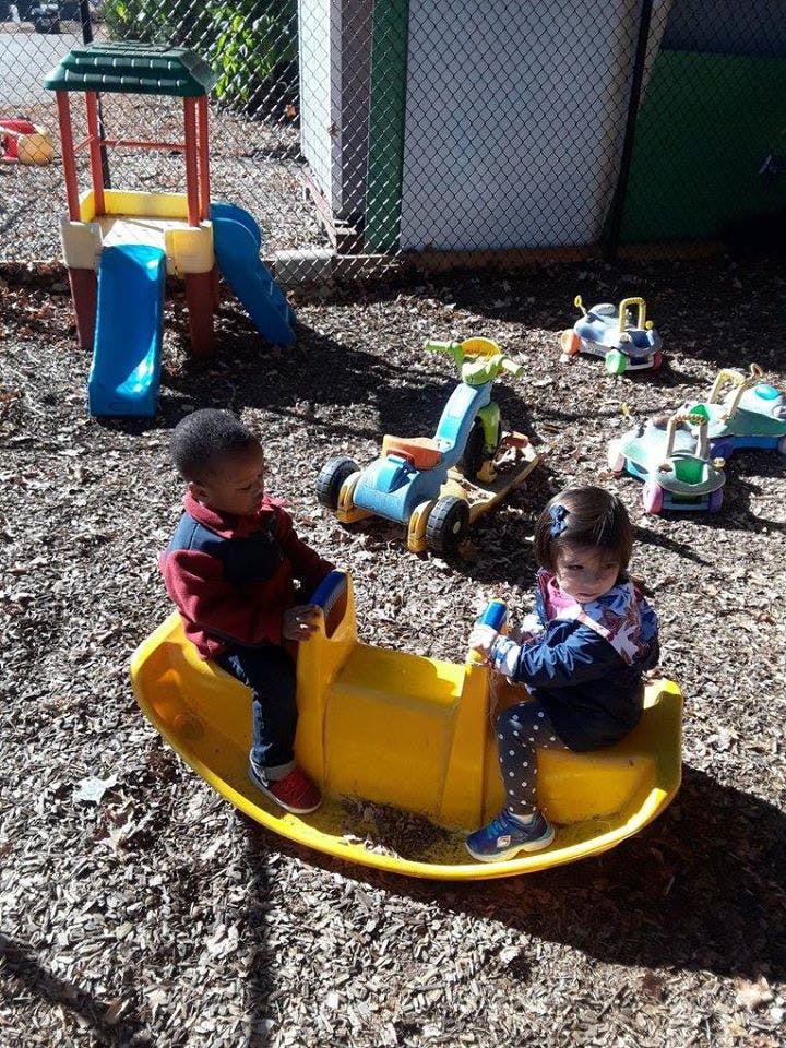Two children on a yellow seesaw in a playground